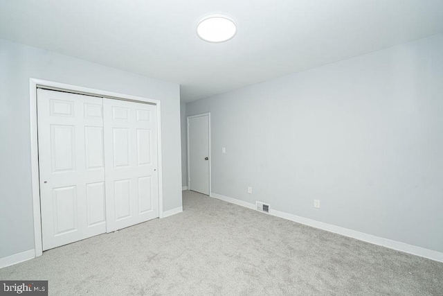 unfurnished bedroom with carpet, a closet, visible vents, and baseboards