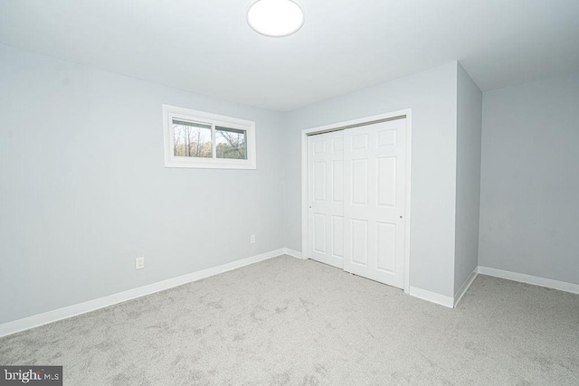 unfurnished bedroom featuring carpet floors, a closet, and baseboards