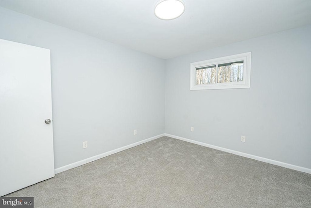 carpeted spare room featuring baseboards