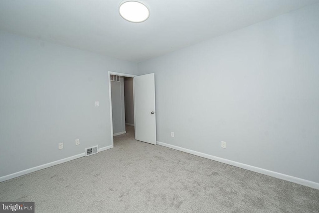 unfurnished room with carpet floors, visible vents, and baseboards