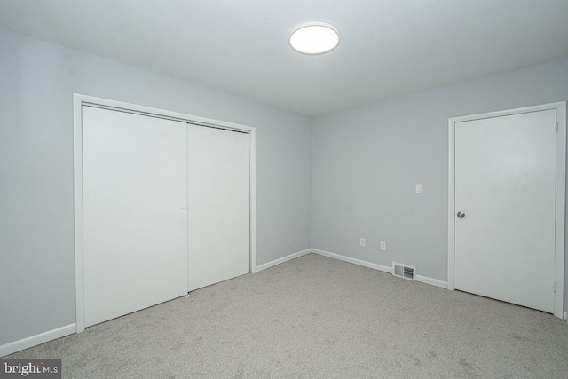 unfurnished bedroom featuring a closet, carpet flooring, visible vents, and baseboards