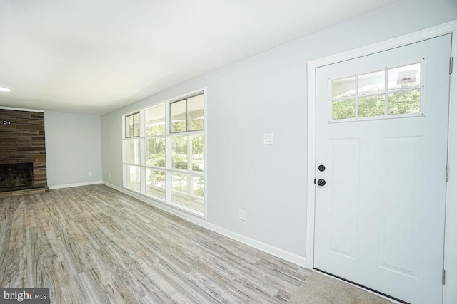 unfurnished living room featuring a large fireplace, light wood-type flooring, and baseboards