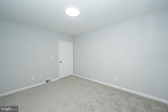 unfurnished room with carpet, visible vents, and baseboards