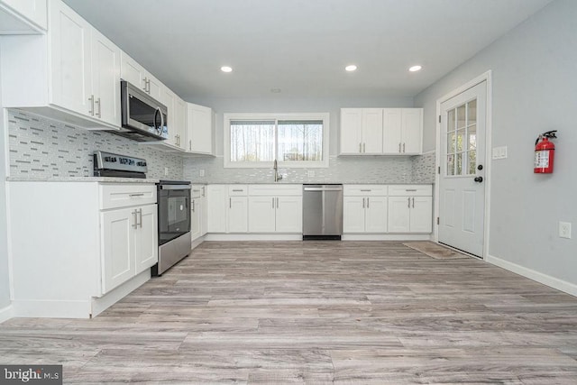 kitchen featuring tasteful backsplash, appliances with stainless steel finishes, white cabinets, and a sink