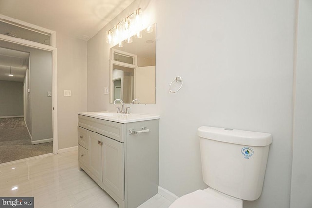 bathroom featuring toilet, baseboards, and vanity