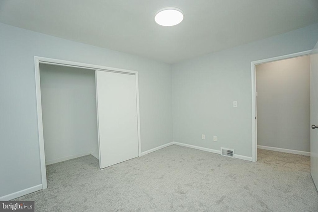 unfurnished bedroom featuring carpet floors, a closet, visible vents, and baseboards