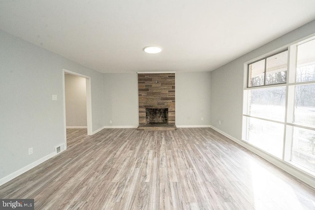 unfurnished living room with a large fireplace, baseboards, and wood finished floors