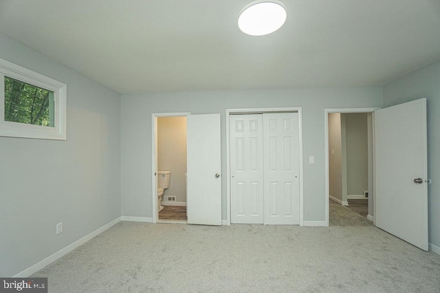 unfurnished bedroom with ensuite bathroom, carpet flooring, visible vents, baseboards, and a closet