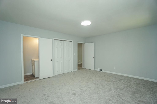 unfurnished bedroom with light colored carpet, a closet, visible vents, and baseboards