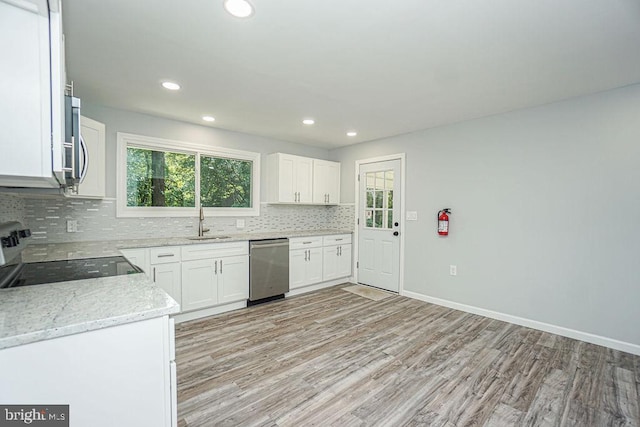 kitchen featuring tasteful backsplash, appliances with stainless steel finishes, light stone countertops, white cabinetry, and a sink