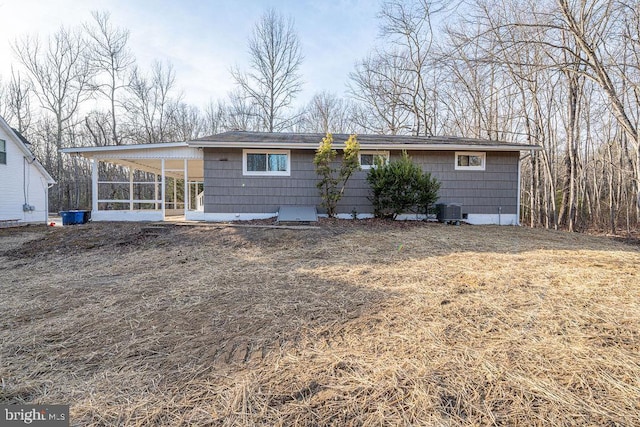 rear view of property with central air condition unit and a sunroom