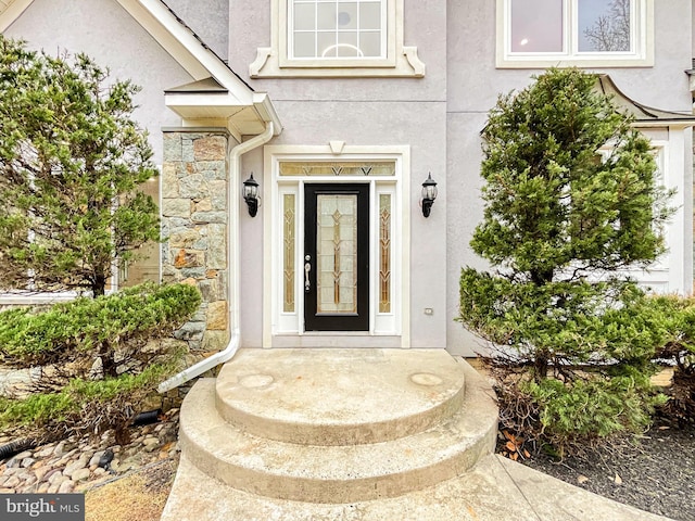 property entrance featuring stone siding and stucco siding