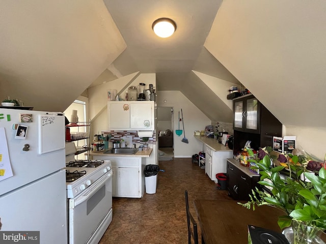 kitchen featuring white appliances, lofted ceiling, light countertops, white cabinetry, and a sink