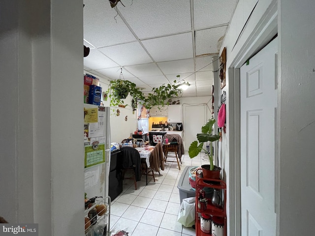 interior space with light tile patterned floors and a drop ceiling