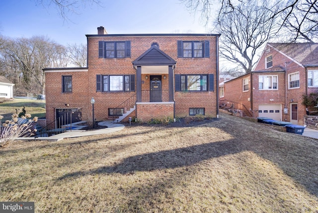 view of front of property with a garage, brick siding, a chimney, and a front yard