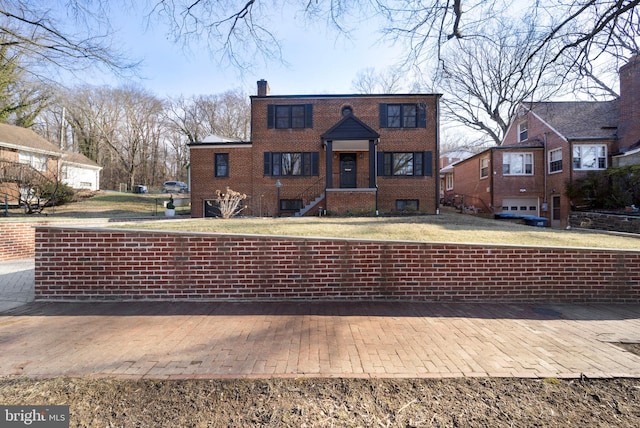 view of front of property featuring a chimney, a front lawn, and brick siding