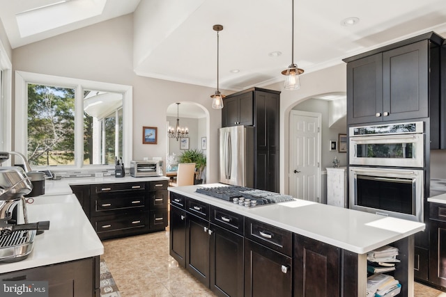 kitchen featuring decorative light fixtures, a toaster, light countertops, arched walkways, and stainless steel appliances