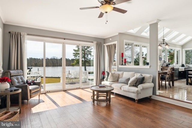 living area featuring crown molding, a water view, lofted ceiling with skylight, ceiling fan with notable chandelier, and wood finished floors