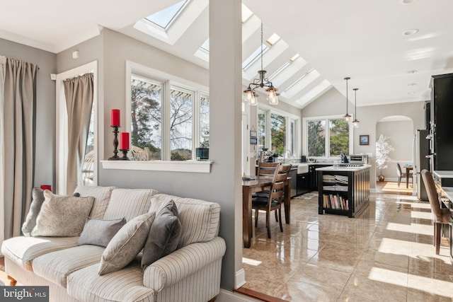 living area with arched walkways, vaulted ceiling with skylight, and baseboards