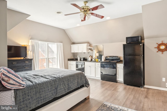 bedroom featuring visible vents, vaulted ceiling, freestanding refrigerator, light wood-style floors, and a sink