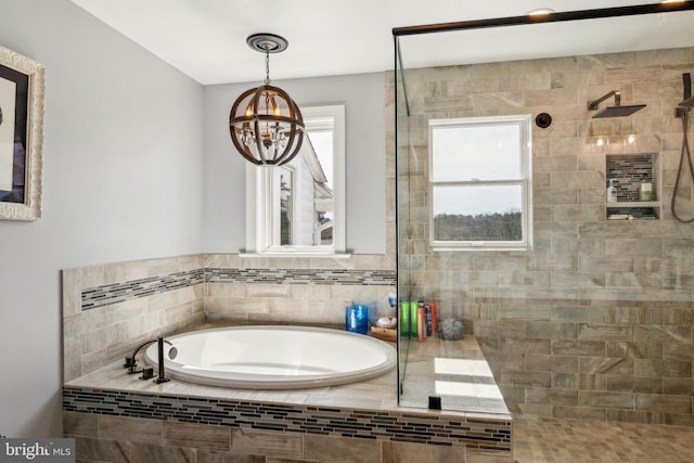 bathroom featuring a garden tub, a notable chandelier, and tiled shower