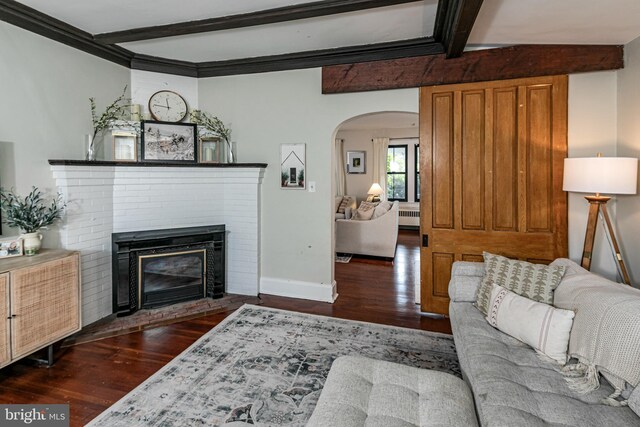 living area with wood finished floors, baseboards, beam ceiling, arched walkways, and a brick fireplace