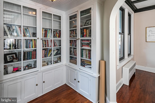 interior details featuring arched walkways, radiator, baseboards, and wood finished floors