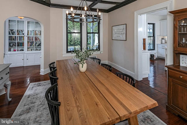 dining area with baseboards, arched walkways, dark wood-style flooring, ornamental molding, and a chandelier