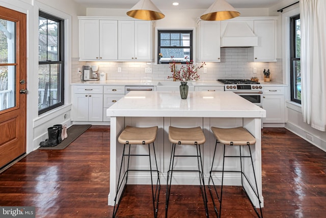 kitchen featuring dark wood finished floors, backsplash, a kitchen breakfast bar, and range with gas cooktop