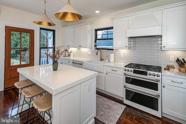 kitchen featuring a kitchen island, a breakfast bar area, range with two ovens, decorative backsplash, and a sink