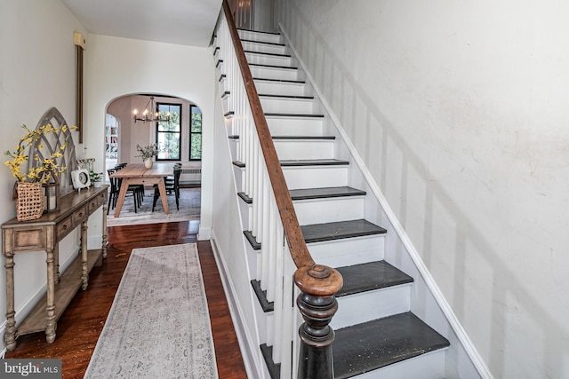 stairs with wood finished floors and arched walkways