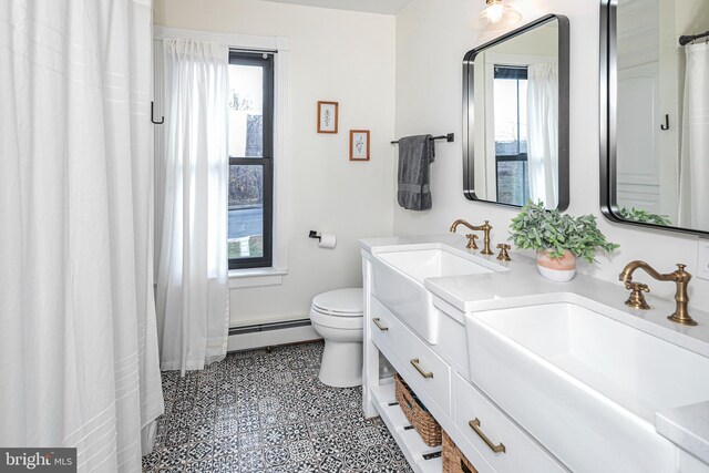 bathroom featuring double vanity, a sink, toilet, and a baseboard radiator