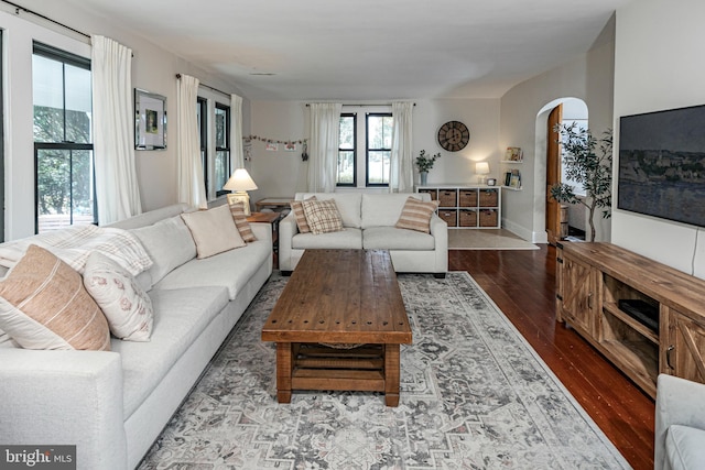 living area with arched walkways and hardwood / wood-style floors