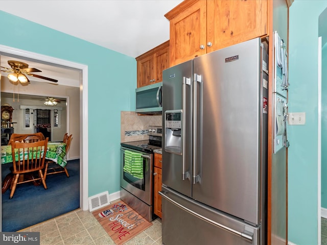 kitchen featuring brown cabinets, tasteful backsplash, visible vents, appliances with stainless steel finishes, and baseboards