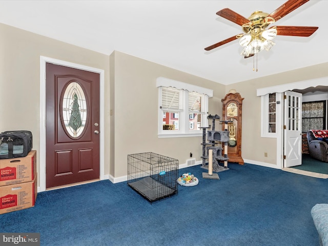 foyer with a ceiling fan, carpet flooring, visible vents, and baseboards