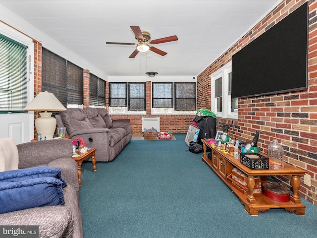 living area featuring a healthy amount of sunlight, brick wall, a ceiling fan, and carpet flooring