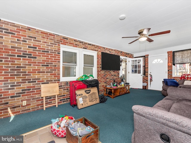 living area featuring carpet, ceiling fan, and brick wall