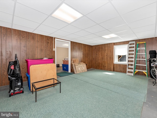 living area with a paneled ceiling and wood walls