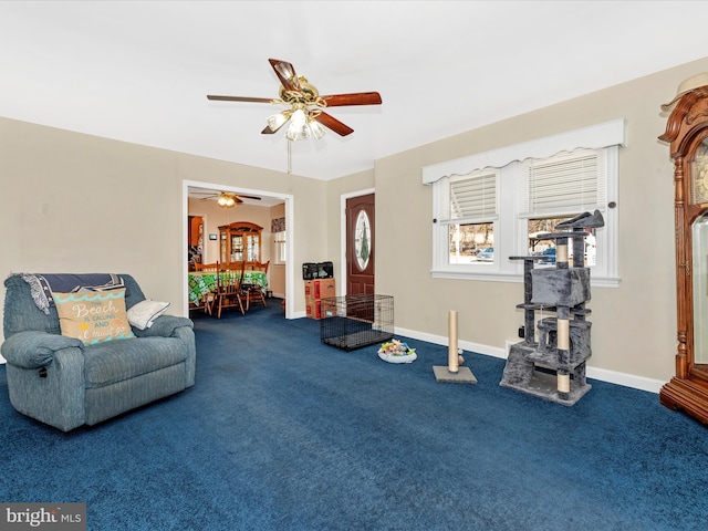 living area featuring carpet, baseboards, and a ceiling fan