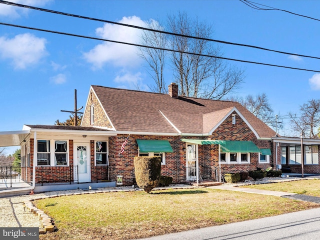 view of front facade with a front lawn, a chimney, a shingled roof, and brick siding