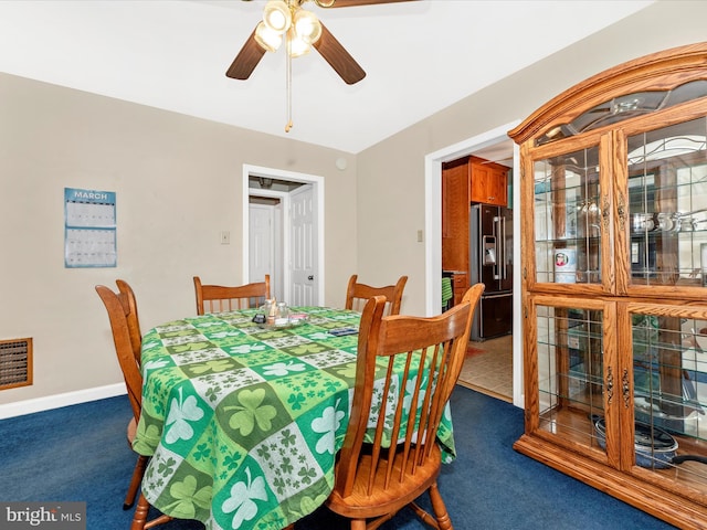 carpeted dining room with a ceiling fan and baseboards