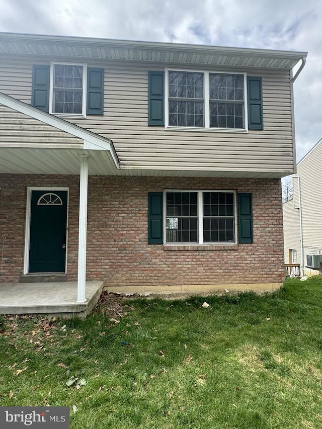 exterior space featuring brick siding, central AC unit, a porch, and a front yard