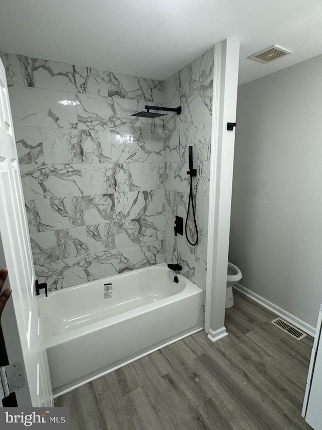 full bathroom with baseboards, visible vents, toilet, wood finished floors, and washtub / shower combination