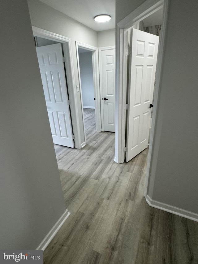 hall with baseboards and wood finished floors