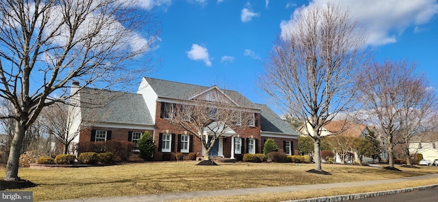 colonial house featuring a front yard and brick siding