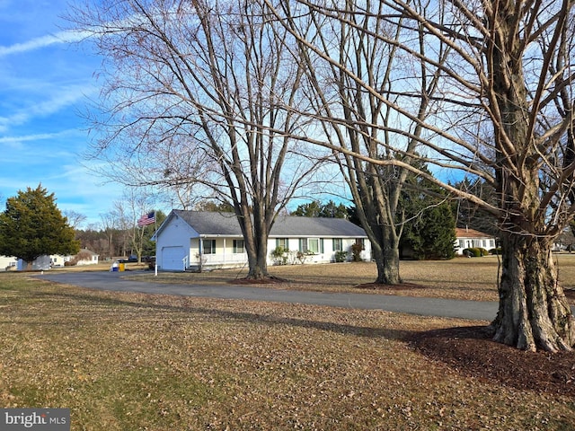 view of front of home featuring aphalt driveway, a front lawn, a chimney, and an attached garage