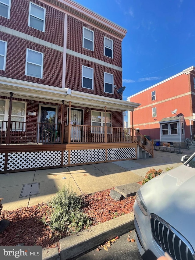 multi unit property featuring a porch and brick siding