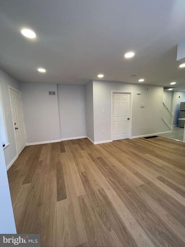 below grade area with recessed lighting, wood finished floors, visible vents, and stairs