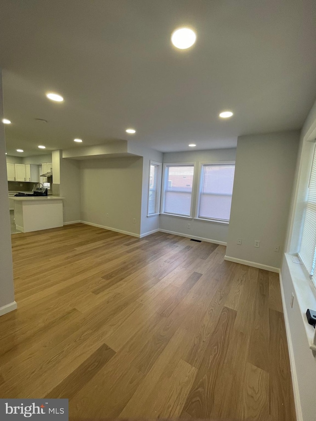 unfurnished living room featuring recessed lighting, light wood-style flooring, and baseboards