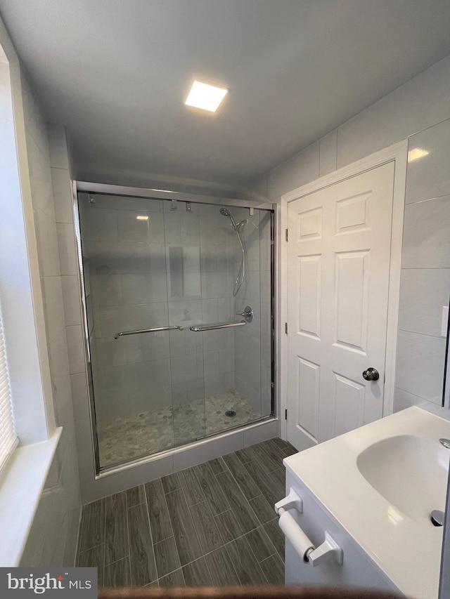 full bath featuring a sink, wood finish floors, and a shower stall